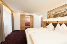 Gemütliches Doppelzimmer mit Holzdetails und Blick auf die Alpen in der Pension Annemarie.