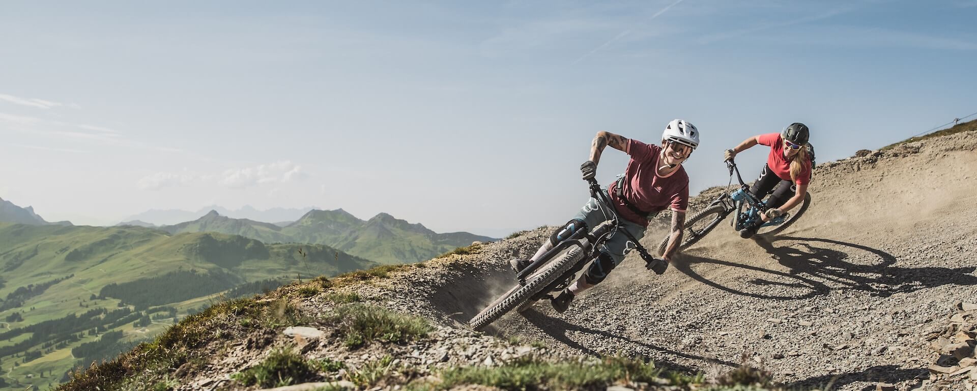 Mountainbiker fahren auf einem kurvenreichen Trail in der alpinen Landschaft.